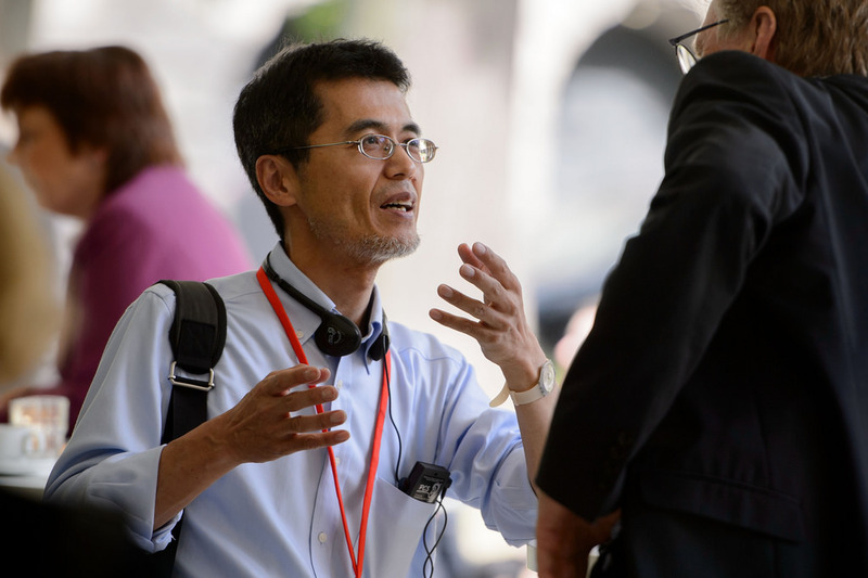 Man in business attire using his hands to to talk with another man.