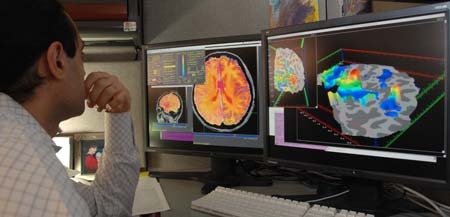 A researcher studies fMRI images on a computer monitor.