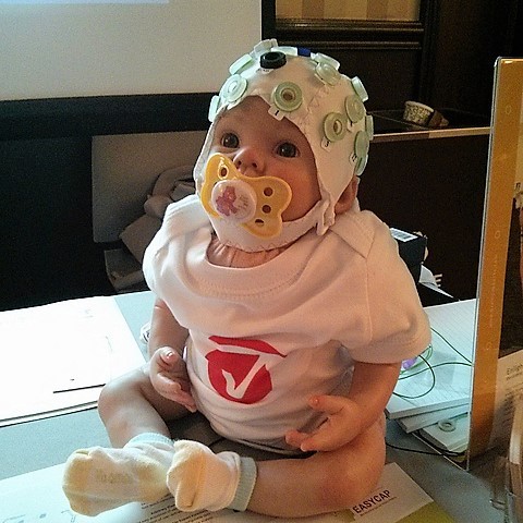 An infant wears an EEG cap.