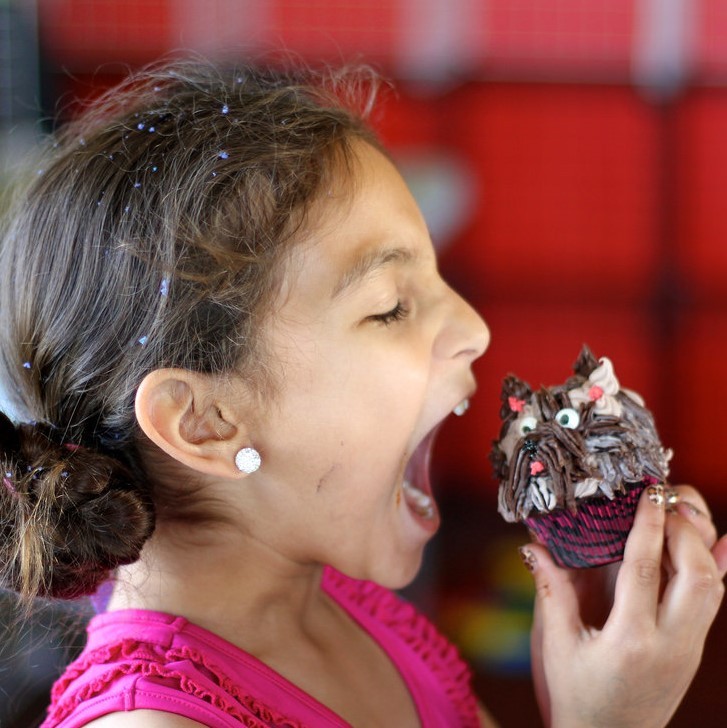 A girls prepares to take a big bite out of a cupcake.