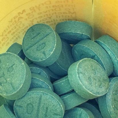 Green Adderall pills in a prescription bottle.