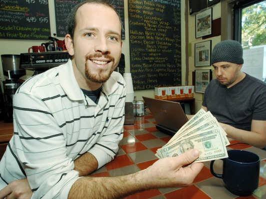 Coffee shop owner Josh cooks shows 100 dollars that were donated by a generous customer to buy drinks for strangers.