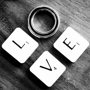 Scrabble tiles and wedding rings spell out the word "Love".