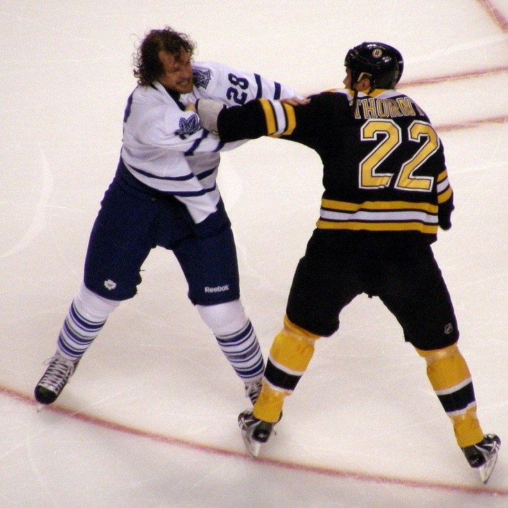 Two professional hockey players fight during a game.