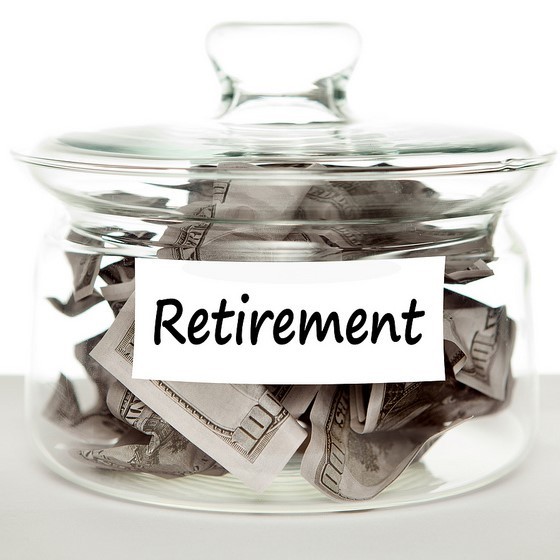 A glass jar labeled "retirement" is filled with cash.