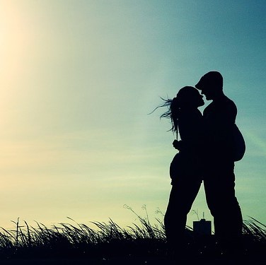 A silhouette of a couple embracing seen against the evening sky. 