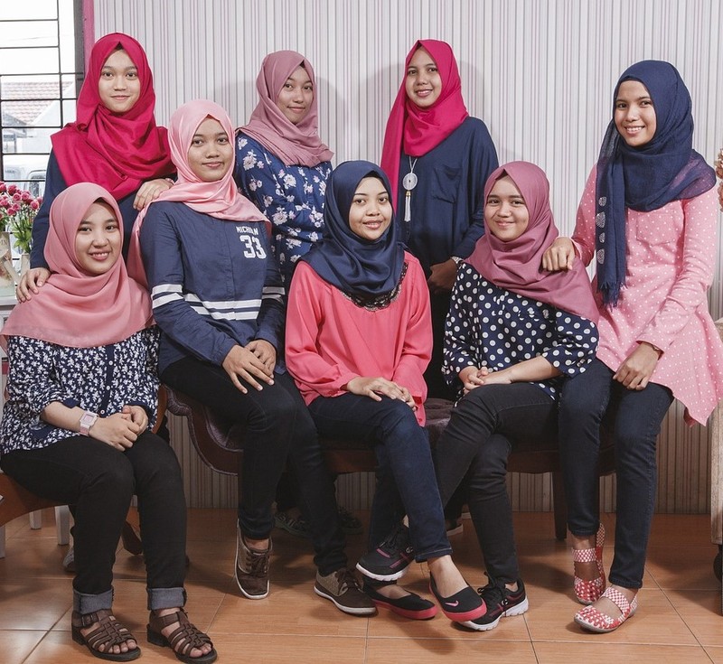 A group of Malaysian teen girls pose for a photo wearing casual clothing and traditional head scarves.