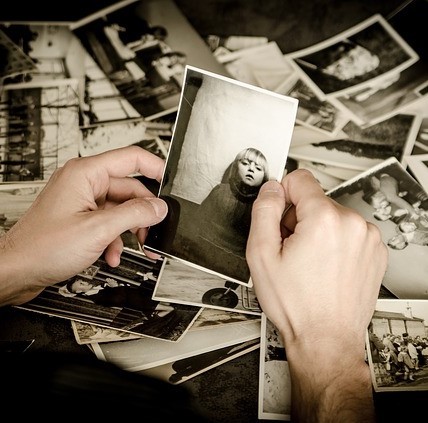 Hands sifting through a box of old photographs.
