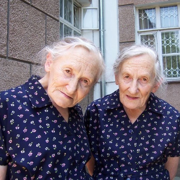75-year old identical twins wearing identical dresses.