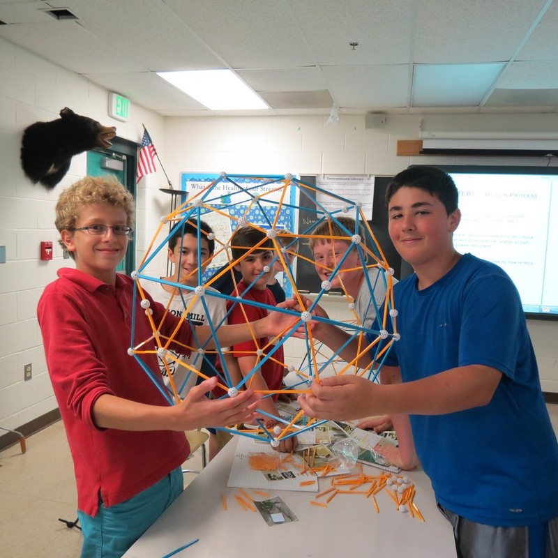 A group of boys at science camp show off the geodesic sphere they've built together.