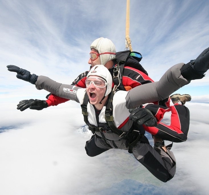 A man yells with excitement during a tandem skydive.