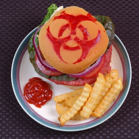 A hamburger with a bio-hazard symbol drawn on the bun with ketchup.