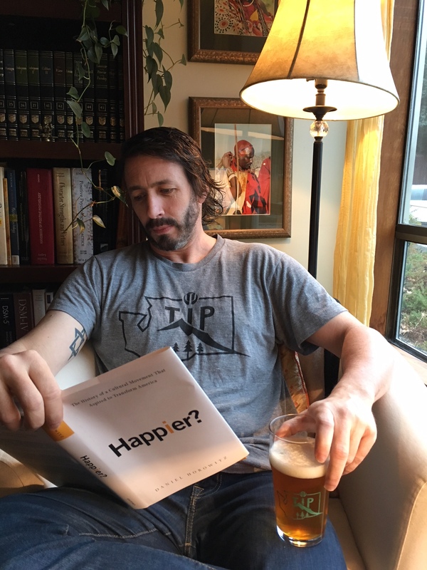 Noba editor Robert Biswas-Diener wearing a TIP NW t-shirt and holding a TIP NW pint glass.