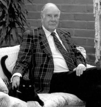 Richard Hamming and a cat seated on a couch, Hamming is wearing a checkered sport coat. 
