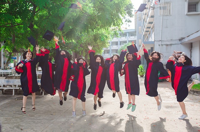 A group of students jumping up for joy having graduated, throwing their caps in the air.