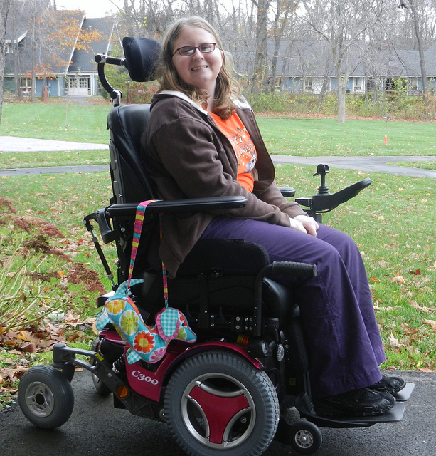 Una mujer sonriente en silla de ruedas motorizada.