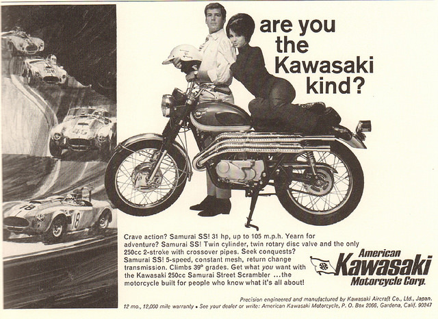 Un anuncio de motocicletas Kawasaki de la década de 1970. El eslogan es ¿Eres del tipo Kawasaki? El anuncio muestra a un hombre de aspecto normal, vestido con camisa y corbata, de pie detrás de una motocicleta Kawasaki y con un casco. Una atractiva mujer se sienta en el asiento de la motocicleta y apoya su cabeza en el hombro del hombre.'s. The slogan is "Are You the Kawasaki Kind?" The ad features an average looking man dressed in a shirt and tie standing behind a Kawasaki motorcycle and holding a motorcycle helmet. An attractive woman sits on the seat of the motorcycle and leans her head on the man's shoulder. 