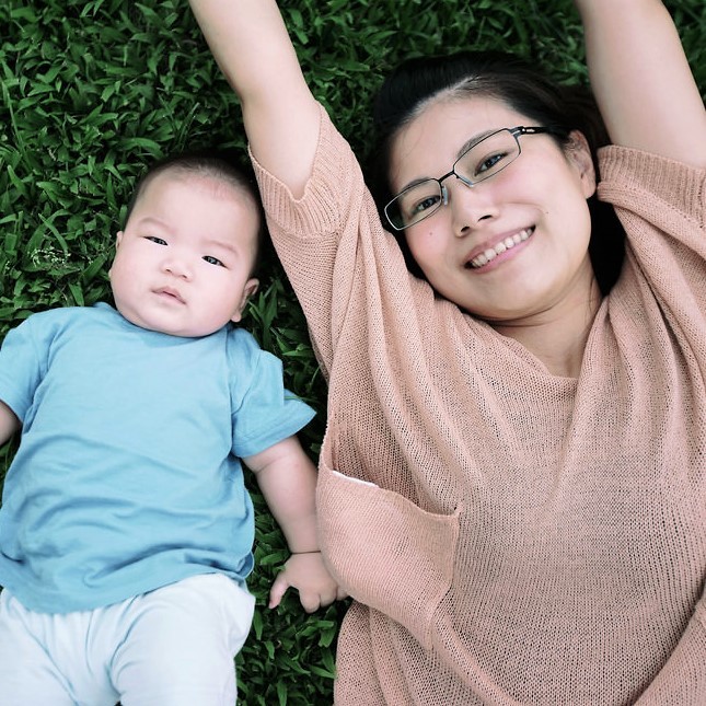 Una madre y un infante yacen juntos sobre la hierba.