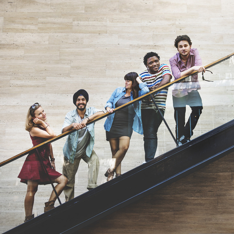 Un grupo de amigos adultos jóvenes se paran juntos en una escalera.