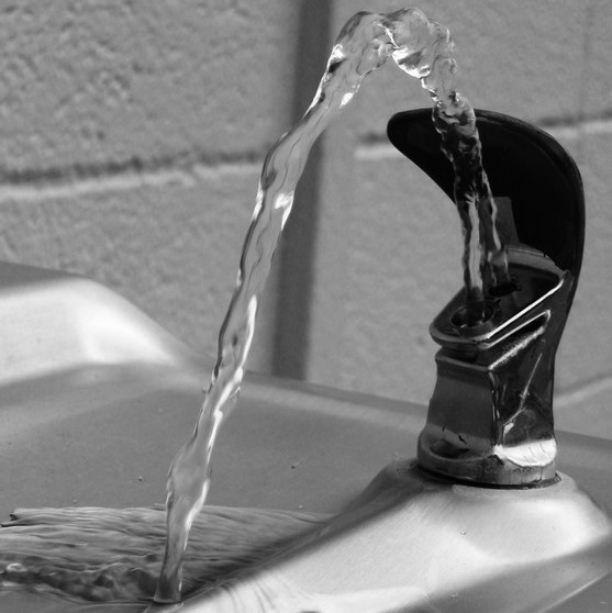 Clear water flows from a public drinking fountain.