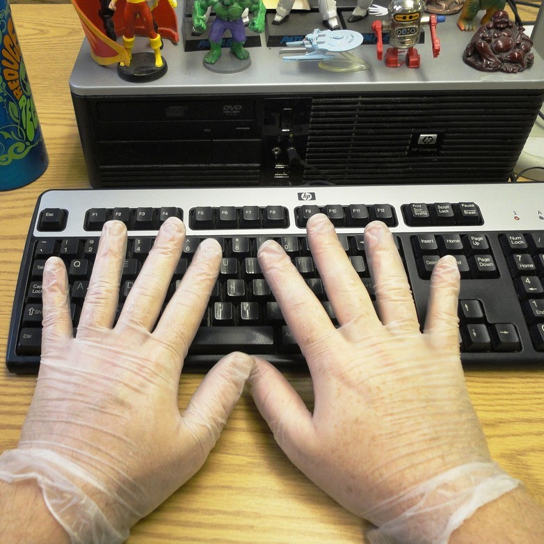 A man wears latex gloves while typing.