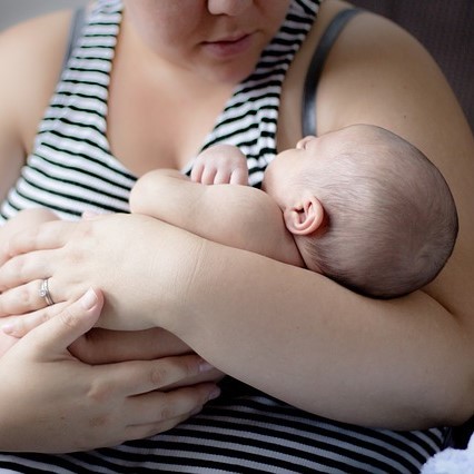 A young mother holds an infant in her arms.