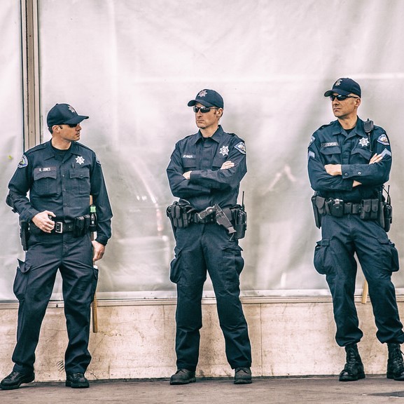 Un grupo de policías uniformados se paran juntos en la acera.