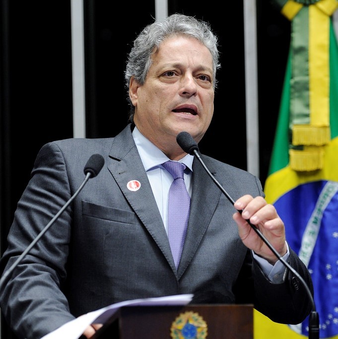 A politician stands behind a lectern and microphone making a speech.