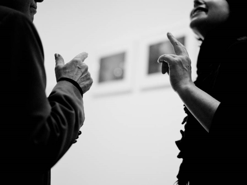 Un hombre y una mujer se dedican a conversar y hacer movimientos idénticos de la mano.