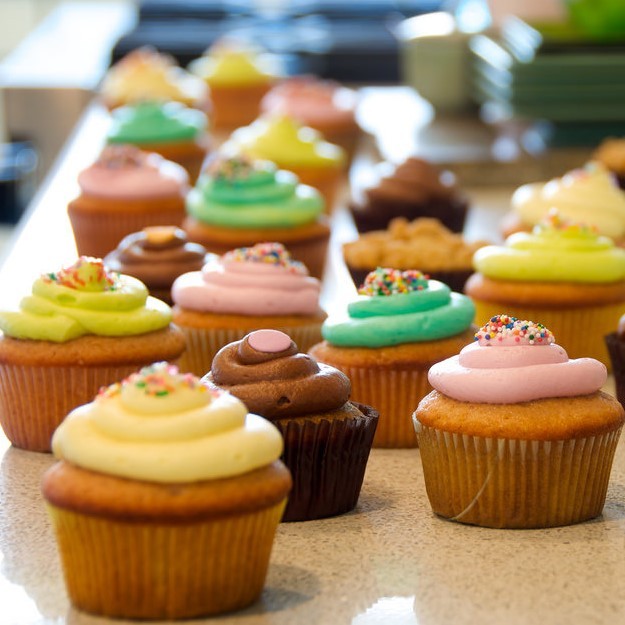 cupcakes and cookies arranged on a table for sale.