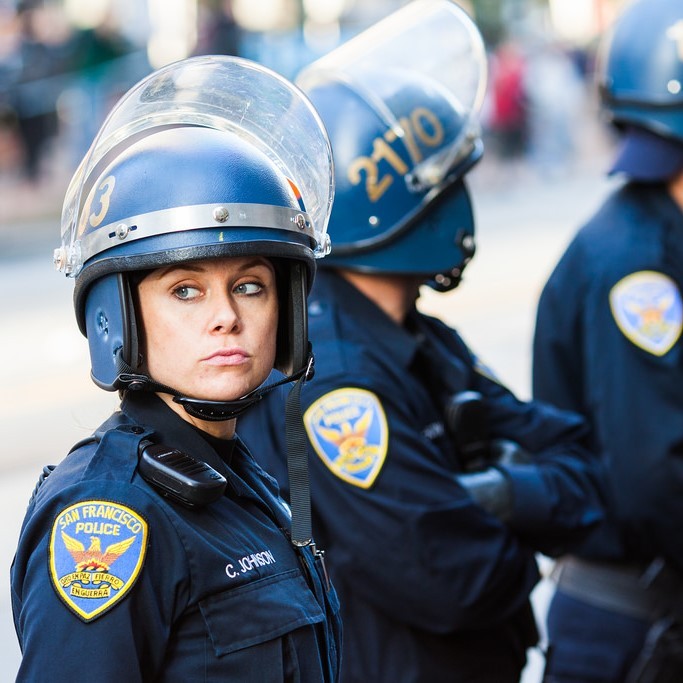 Un grupo de policías que escuchan cascos y protectores faciales.