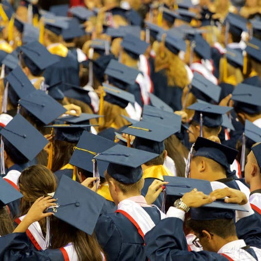 Egresados universitarios se paran con gorras y batas durante una ceremonia de graduación.