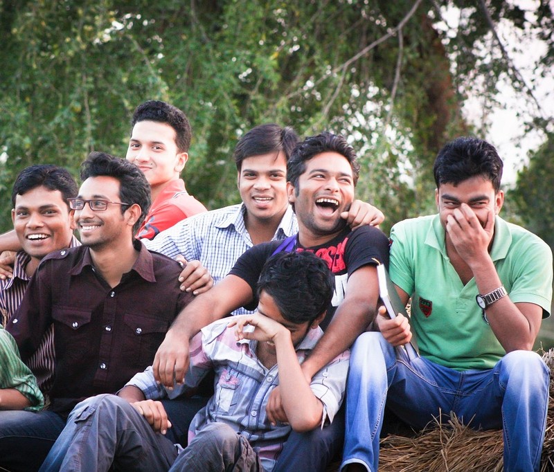 Un grupo de jóvenes se sientan juntos riendo y sonriendo.