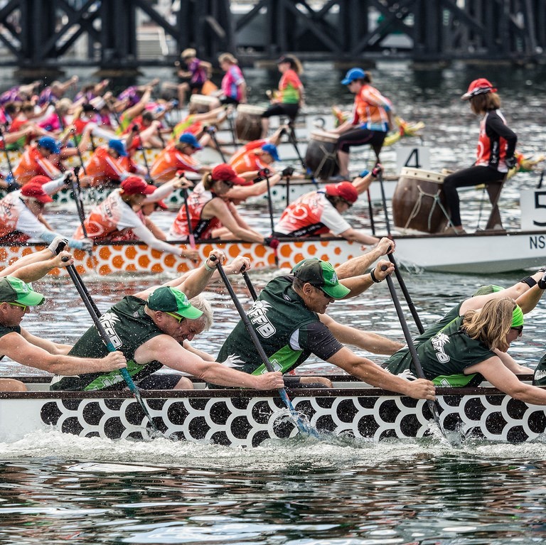 Boats filled with teams of rowers compete in a race.