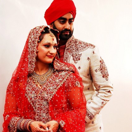 Una joven pareja posando para fotos de boda con vestimenta tradicional india.