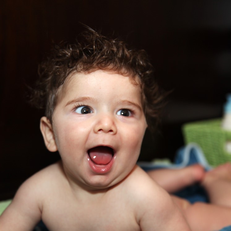 An infant showing a big open-mouthed grin.