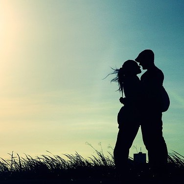 A silhouette of a couple embracing seen against the evening sky.