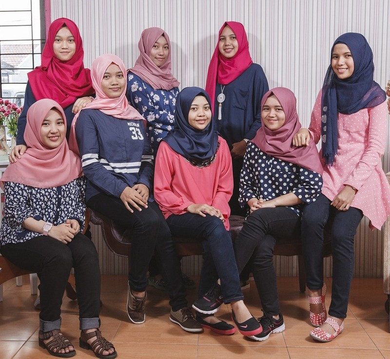 Un grupo de chicas adolescentes malasias posan para una foto vistiendo ropa casual y pañuelos tradicionales en la cabeza.