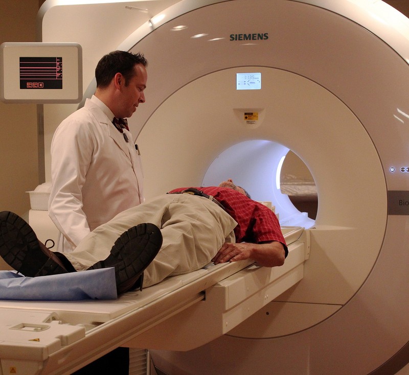A doctor speaks to a patient who is lying on an fMRI table before undergoing a scan.