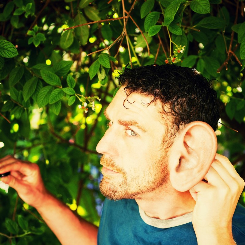 Un hombre pone su mano detrás de su oreja inusualmente grande como si tratara de localizar la ubicación de un sonido.