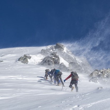 Un grupo de montañeros que suben a una cumbre nevada.