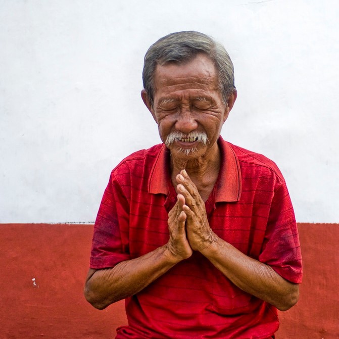 A man closes his eyes and puts his palms together in front of his heart as a symbol of gratitude.