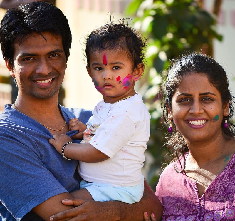 An Indian mother and father pose for a photo with their son who has had his face painted during a religious festival.