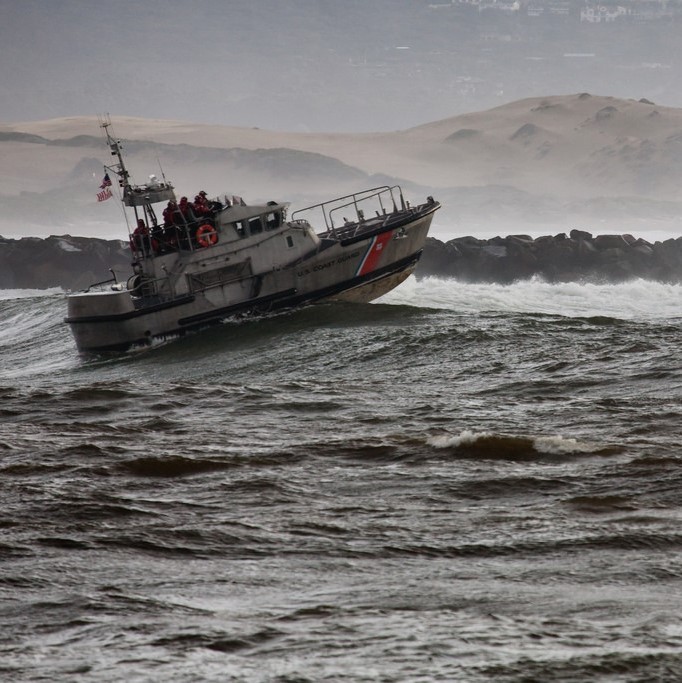 Un pequeño barco de guardacostas se mueve a través de grandes olas oceánicas.