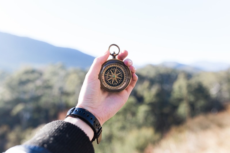 A hiker holds out a compass to get a bearing.