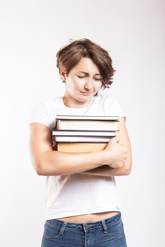 A female student with a pained expression clutches a stack of textbooks