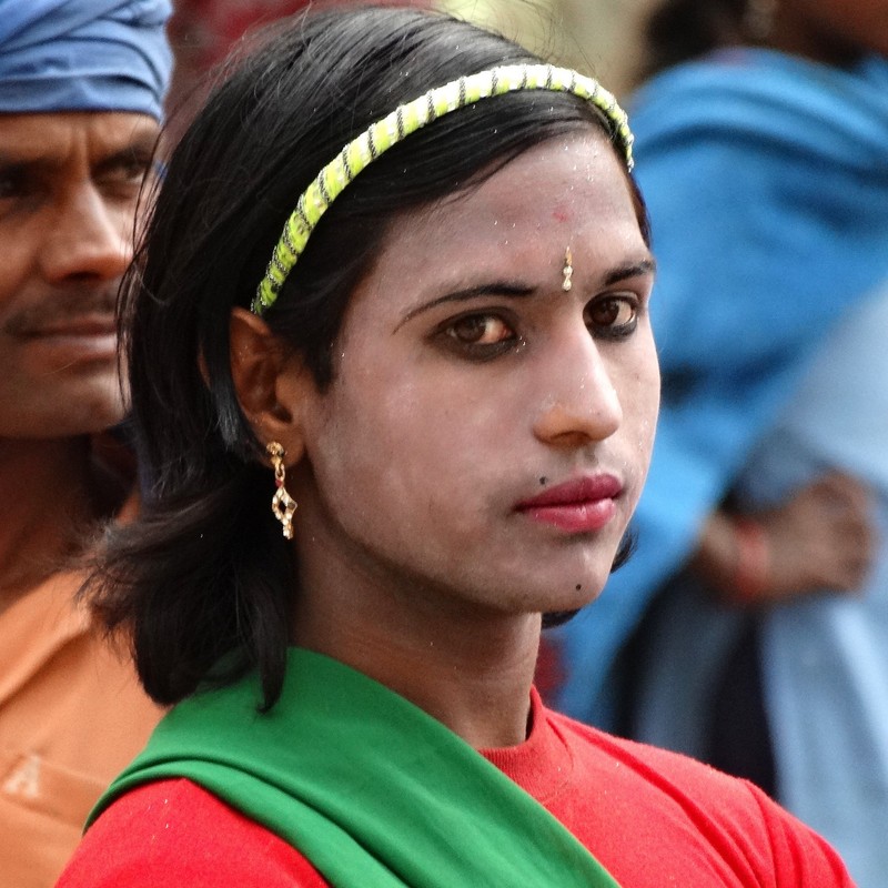 Bailarina hijra de aspecto femenino con delineador de ojos, pintalabios y aretes.