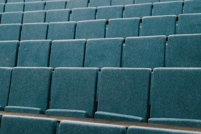 Image of empty teal seats on the dais in a classroom