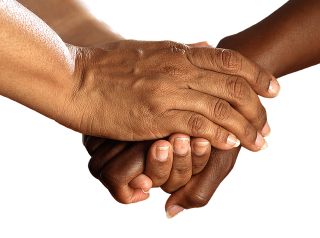Two people holding hands in a supporting manner