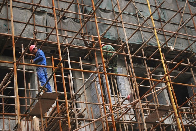 Workers standing on a scaffolding outside of a building construction site